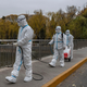 Epidemic control workers wear PPE to protect against the spread of covid-19 as they disinfect an area on the Liangma River, a popular spot for local residents and the site of a protest against covid measures the day before, on November 28, 2022